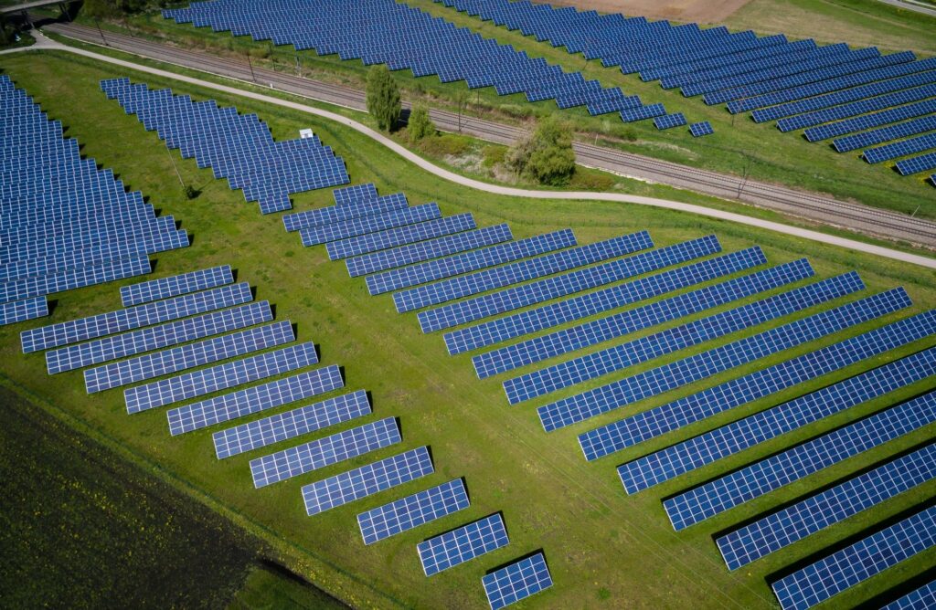 Zonnepanelen naast spoorweg in veld, gefotografeerd van bovenaf - Zonnepanelen uitschakelen