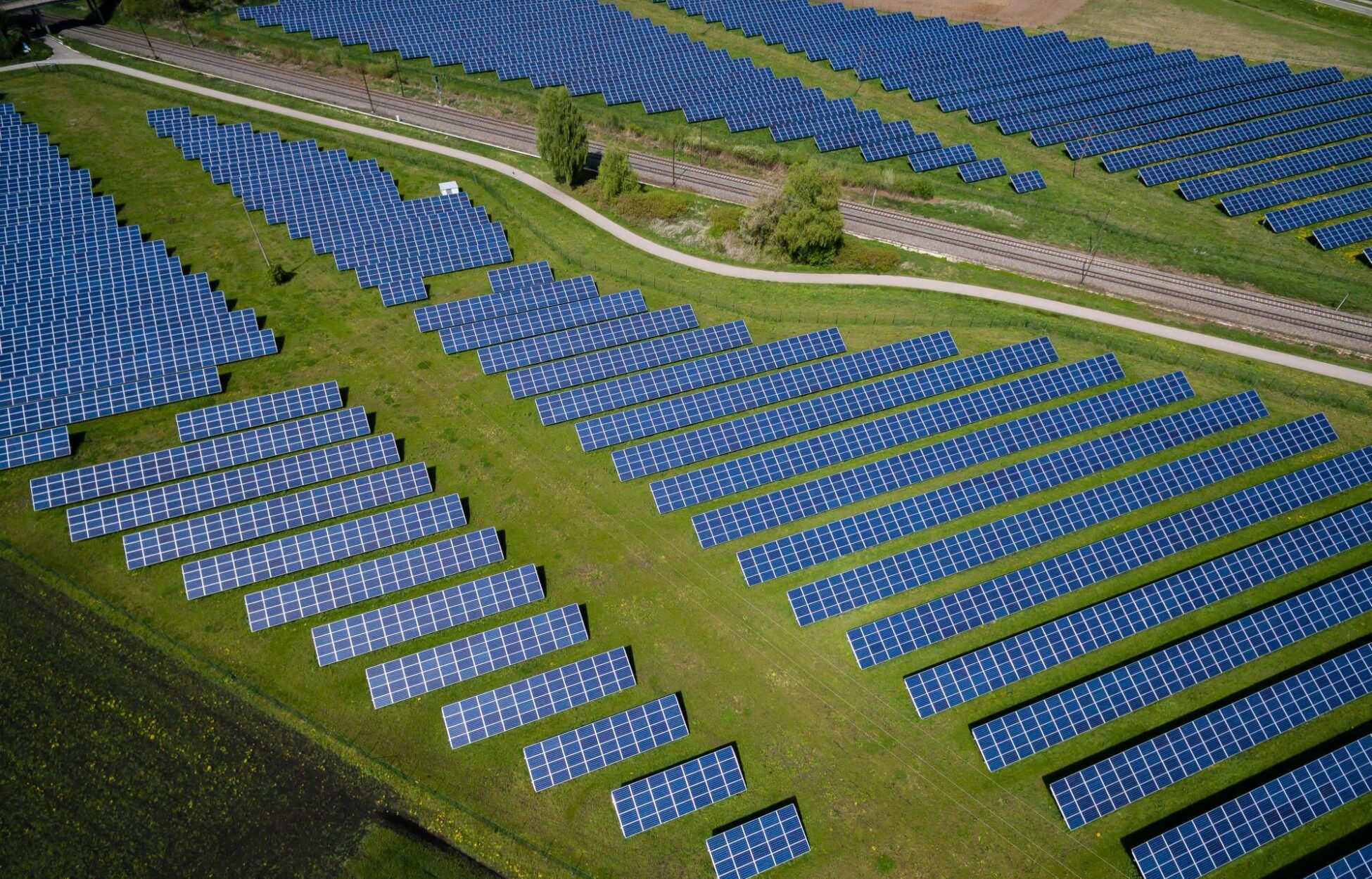 Zonnepanelen naast spoorweg in veld, gefotografeerd van bovenaf - Zonnepanelen uitschakelen